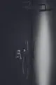 Duschelement mit Regenbrause und Handbrause, an einer dunklen Wand montiert. Produktelemente von Ideal Standard sind zu sehen.